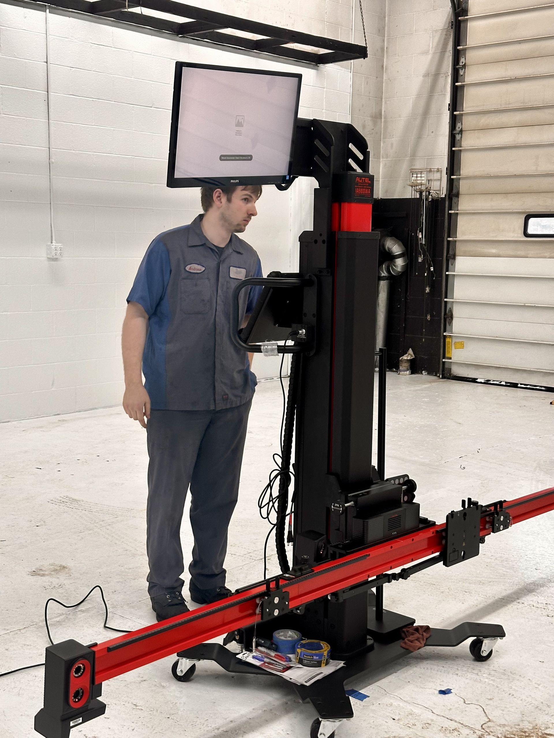 Mechanic using a wheel alignment machine in a shop. | West Michigan A.D.A.S and red.