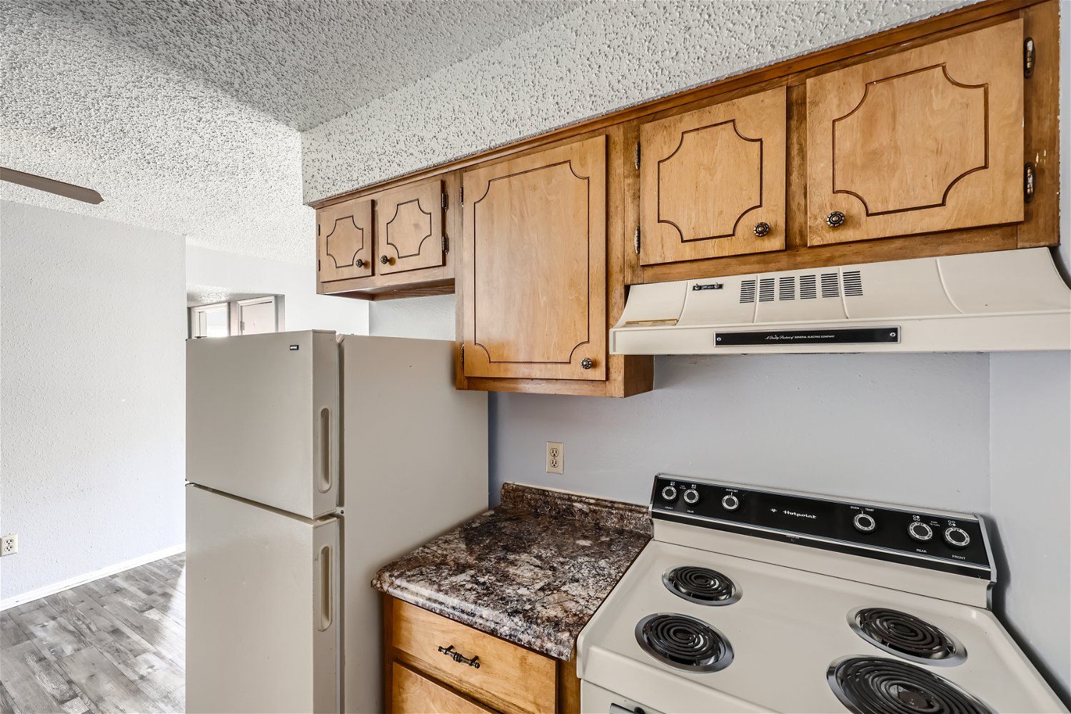 Kitchen with wooden cabinets, white appliances, and a granite countertop.