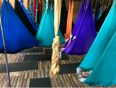 Colorful hammocks and hanging seats in an indoor relaxation area with striped flooring and hanging ropes
