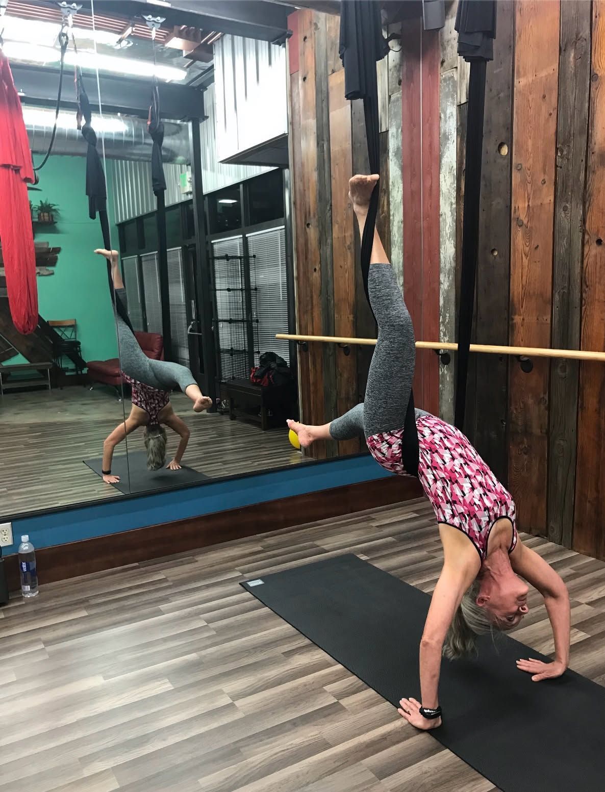 Woman doing a handstand stretch on a yoga mat in a mirrored studio