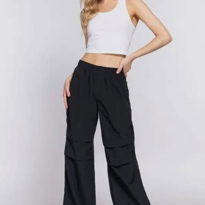 Woman in white crop top and black wide-leg pants. She's standing and posing. Level Up Falcon