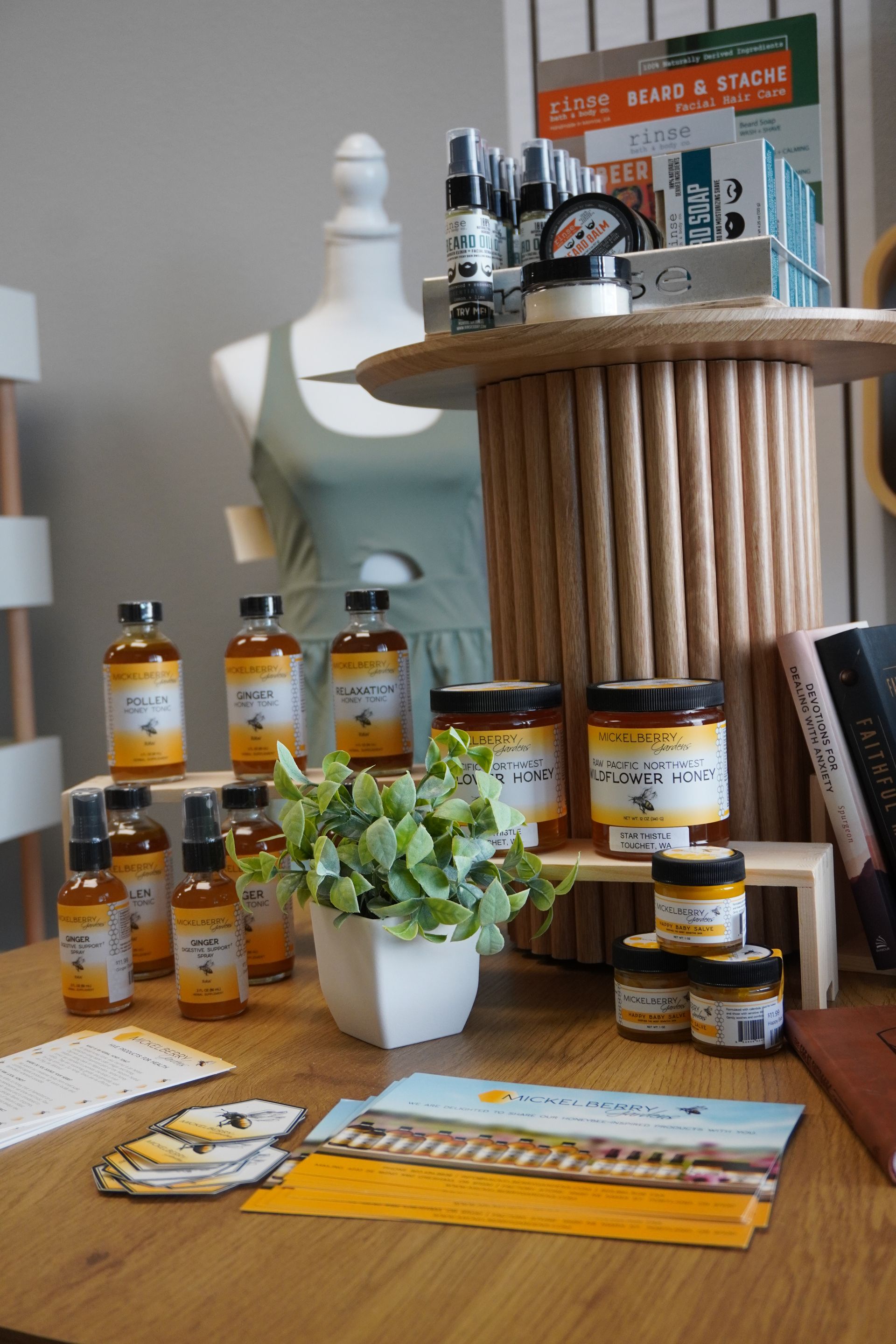Display of honey products, cards, and a dress, on a table. Includes a mannequin, plants, and a spool display. Level Up Falcon