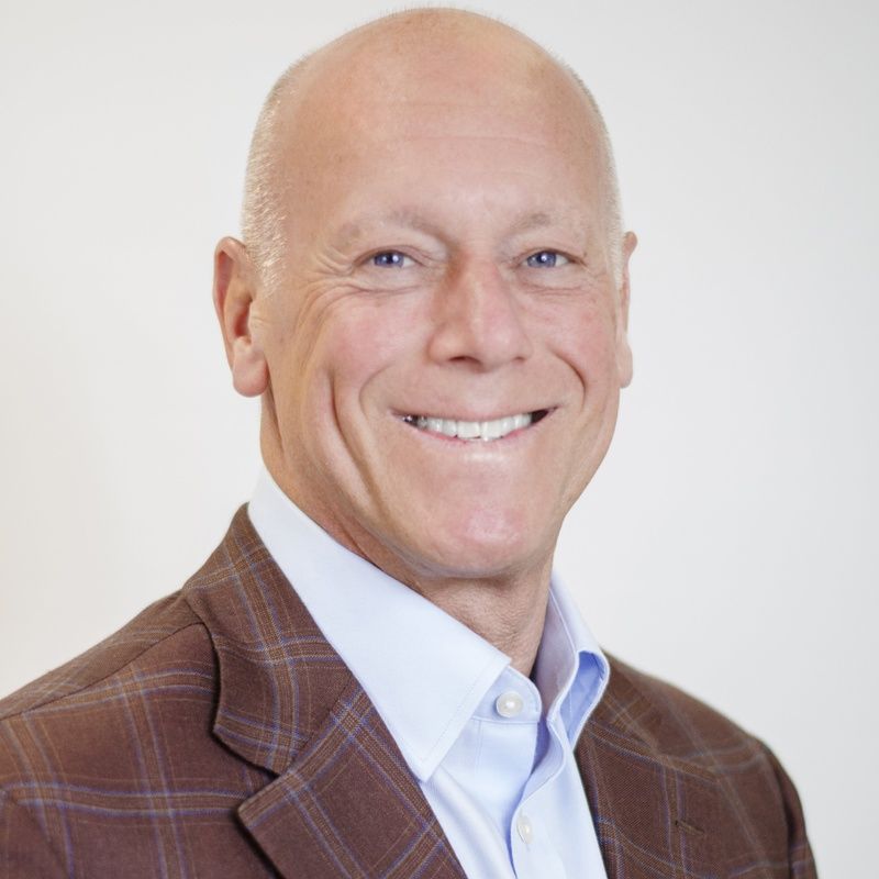 A man in a suit and white shirt is smiling for the camera.
