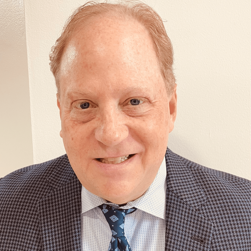 A man in a suit and white shirt is smiling for the camera.