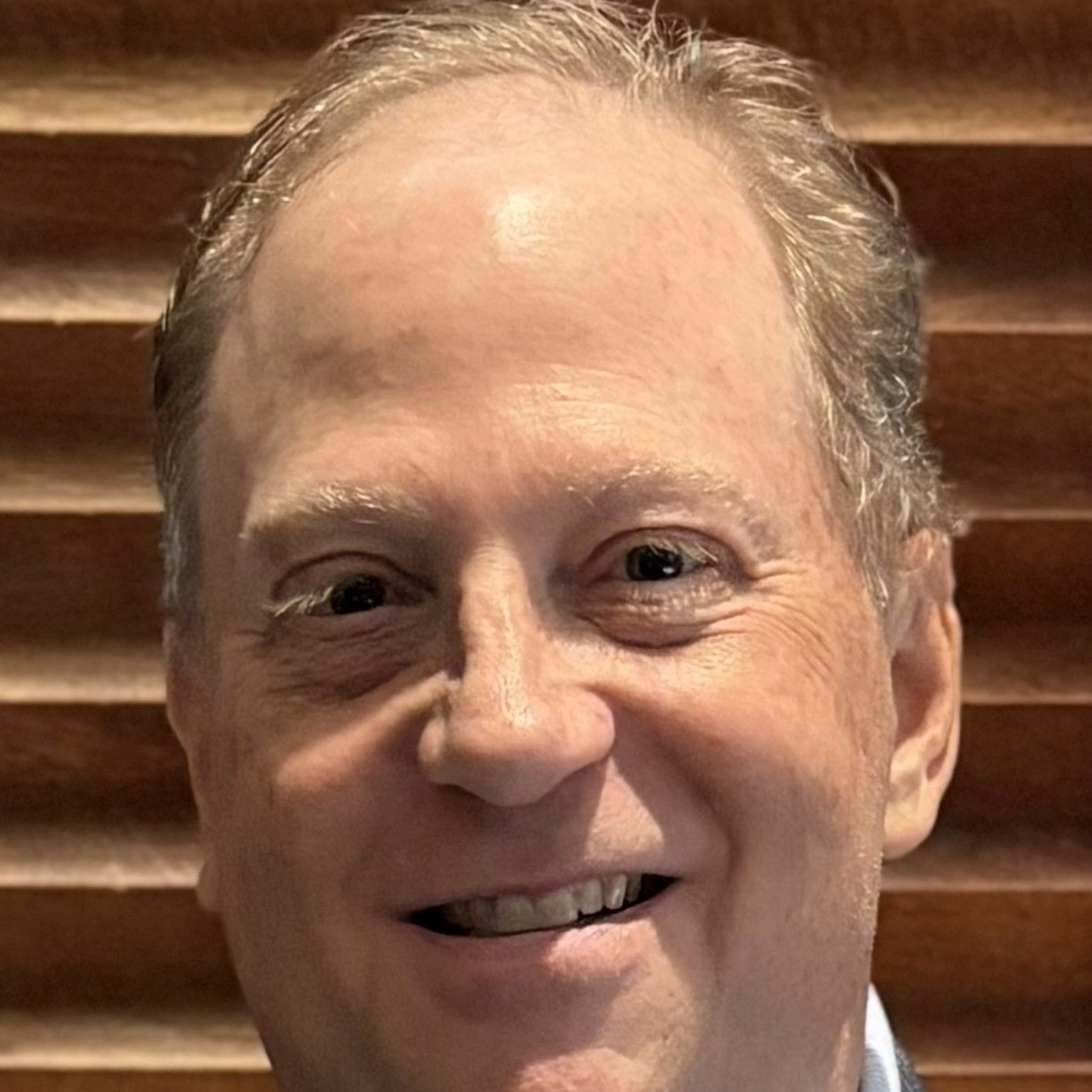 A man in a suit and white shirt is smiling for the camera.
