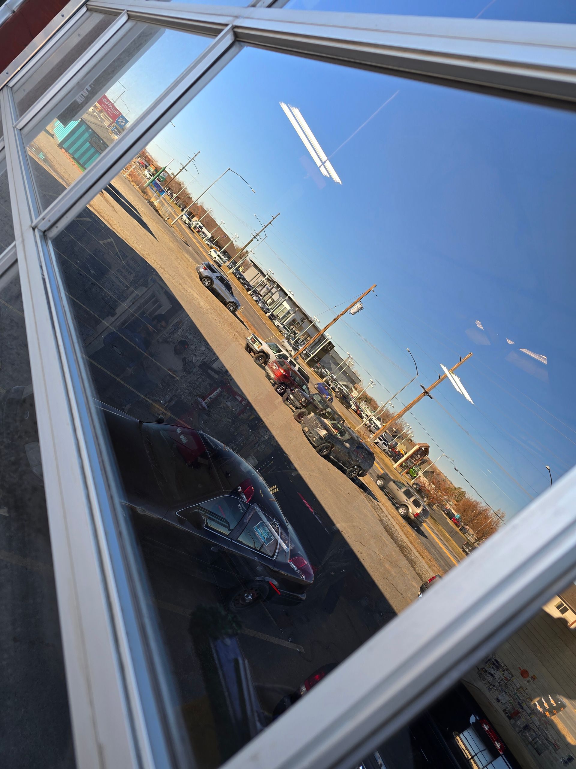A parking lot is reflected in the window of a building