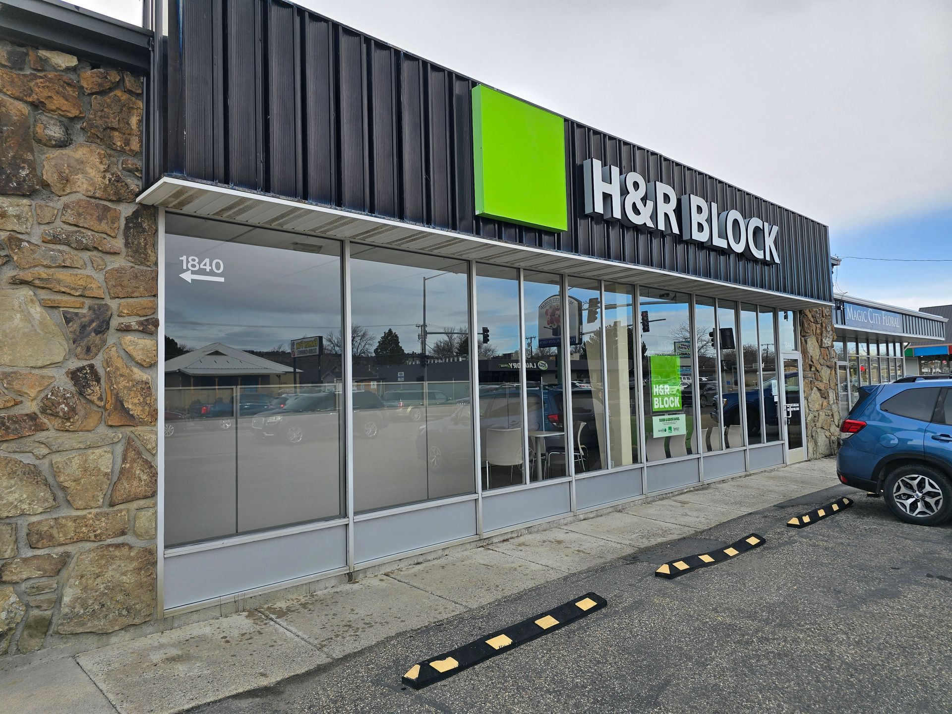 A h & r block store with a car parked in front of it.