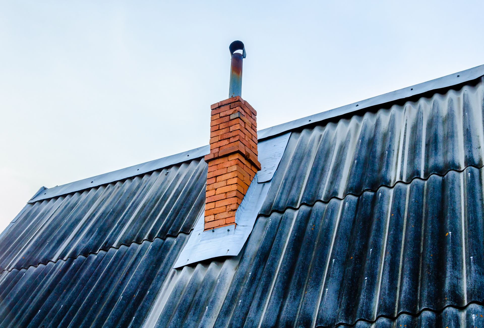A brick chimney is on the roof of a house.