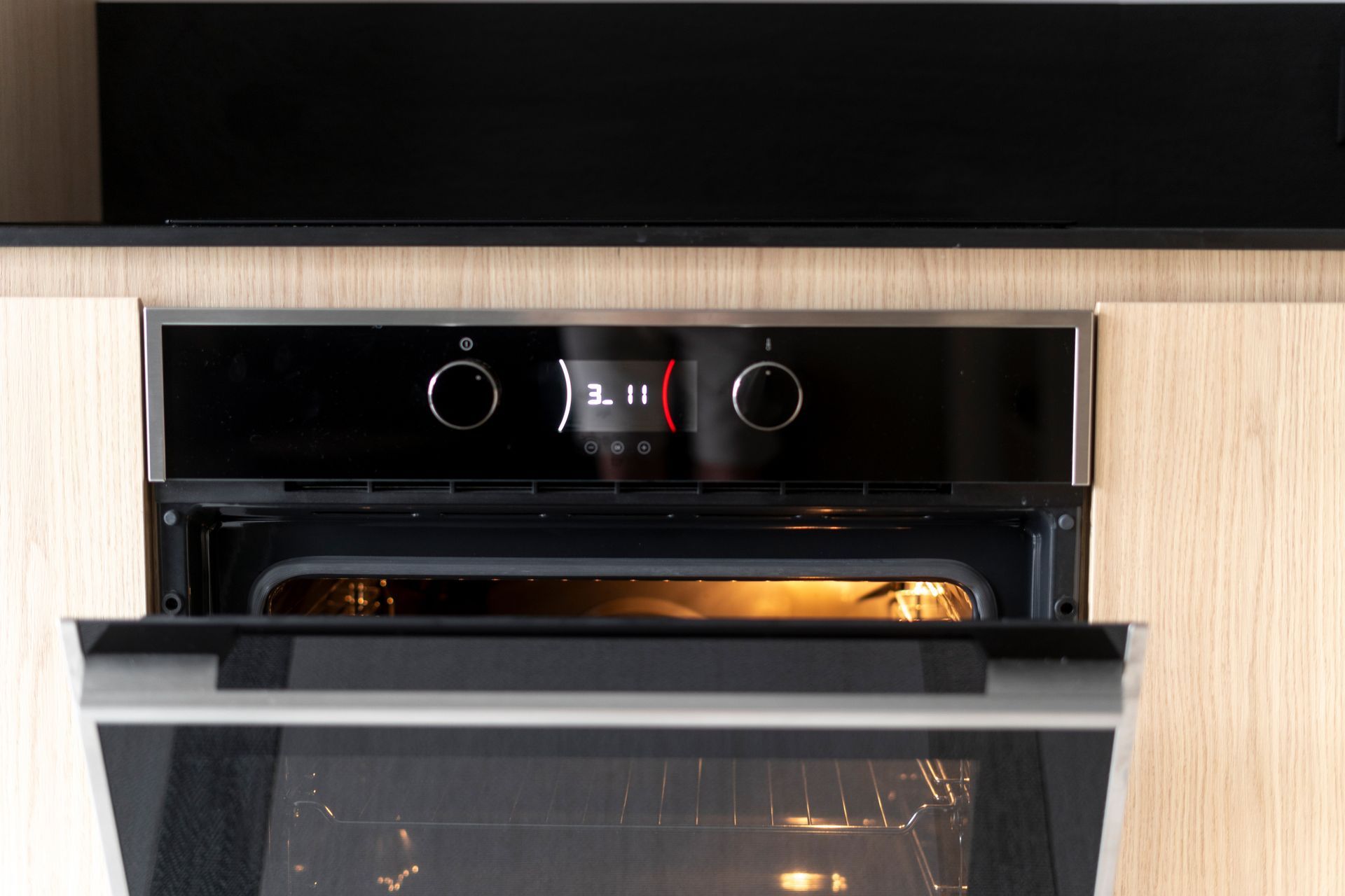 A stainless steel oven with the door open in a kitchen.