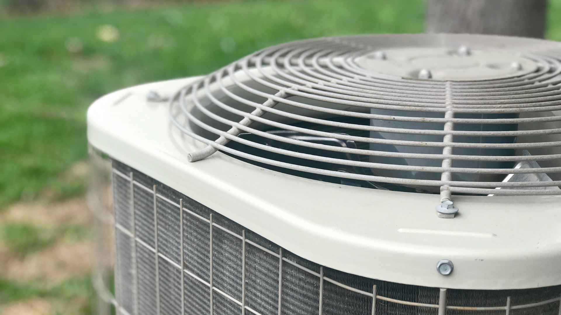 A close up of an air conditioner outside in the grass.