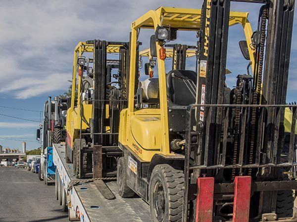 A Row Of Yellow Forklifts Are Sitting On Top Of A Flatbed Truck — RJN Transport In Coonabarabran, NSW
