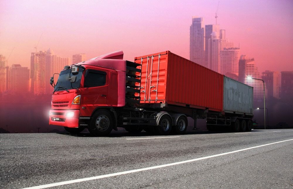 A Red Semi Truck Is Driving Down A Highway — RJN Transport In Inverell, NSW