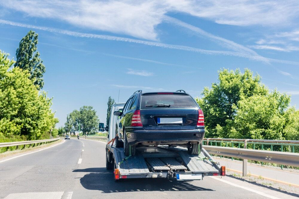 A Car Is Being Towed Down A Highway By A Tow Truck — RJN Transport In Gunnedah, NSW