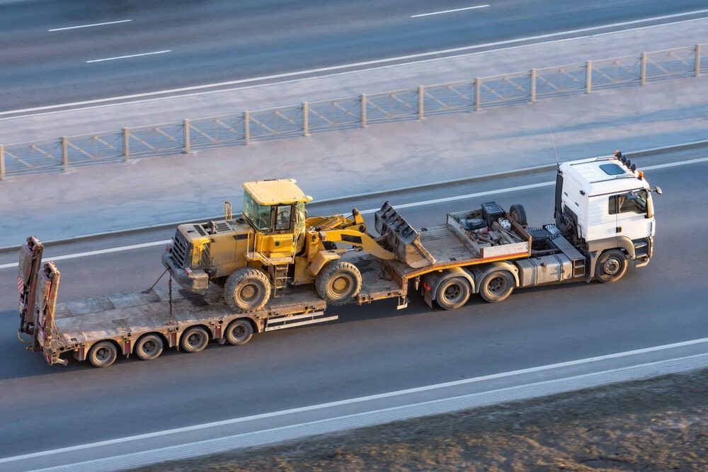 A Truck Is Carrying A Bulldozer On A Trailer On A Highway — RJN Transport In Narrabri, NSW