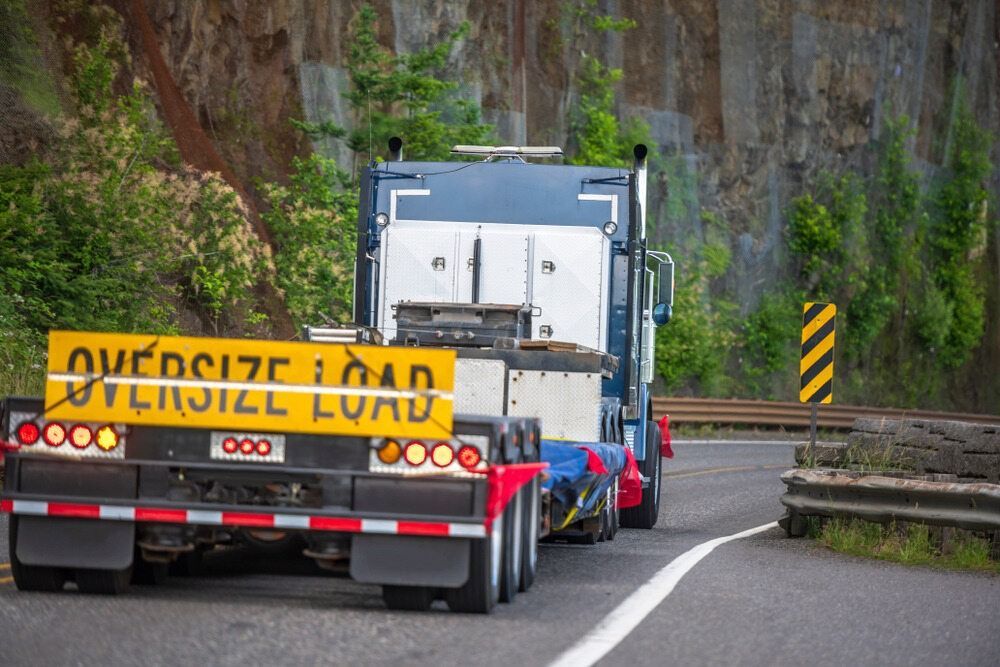 A Semi Truck Is Driving Down A Road With A Yellow Sign On The Back — RJN Transport In Narrabri, NSW