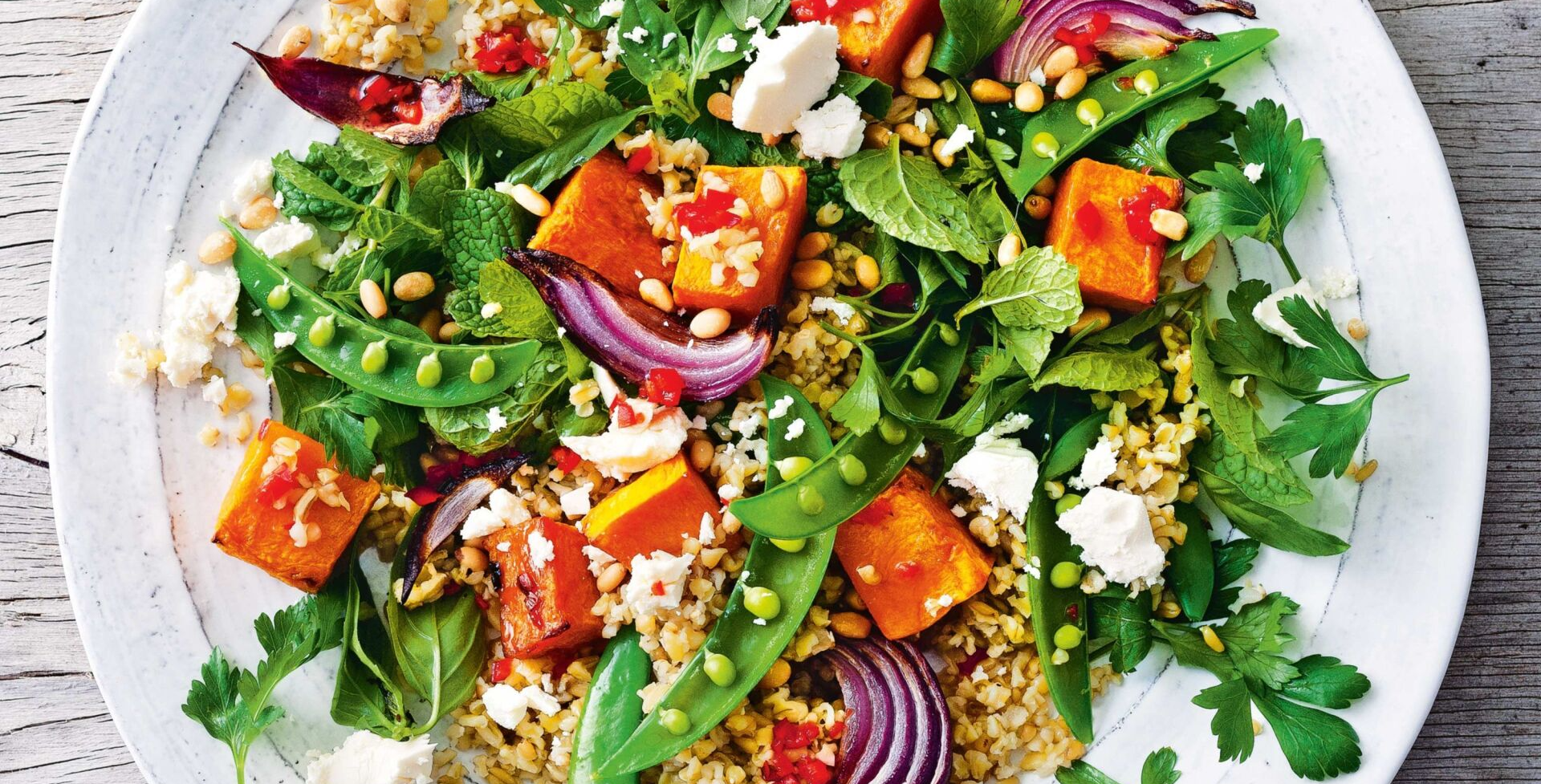 Un plato blanco cubierto con una ensalada de verduras y arroz.