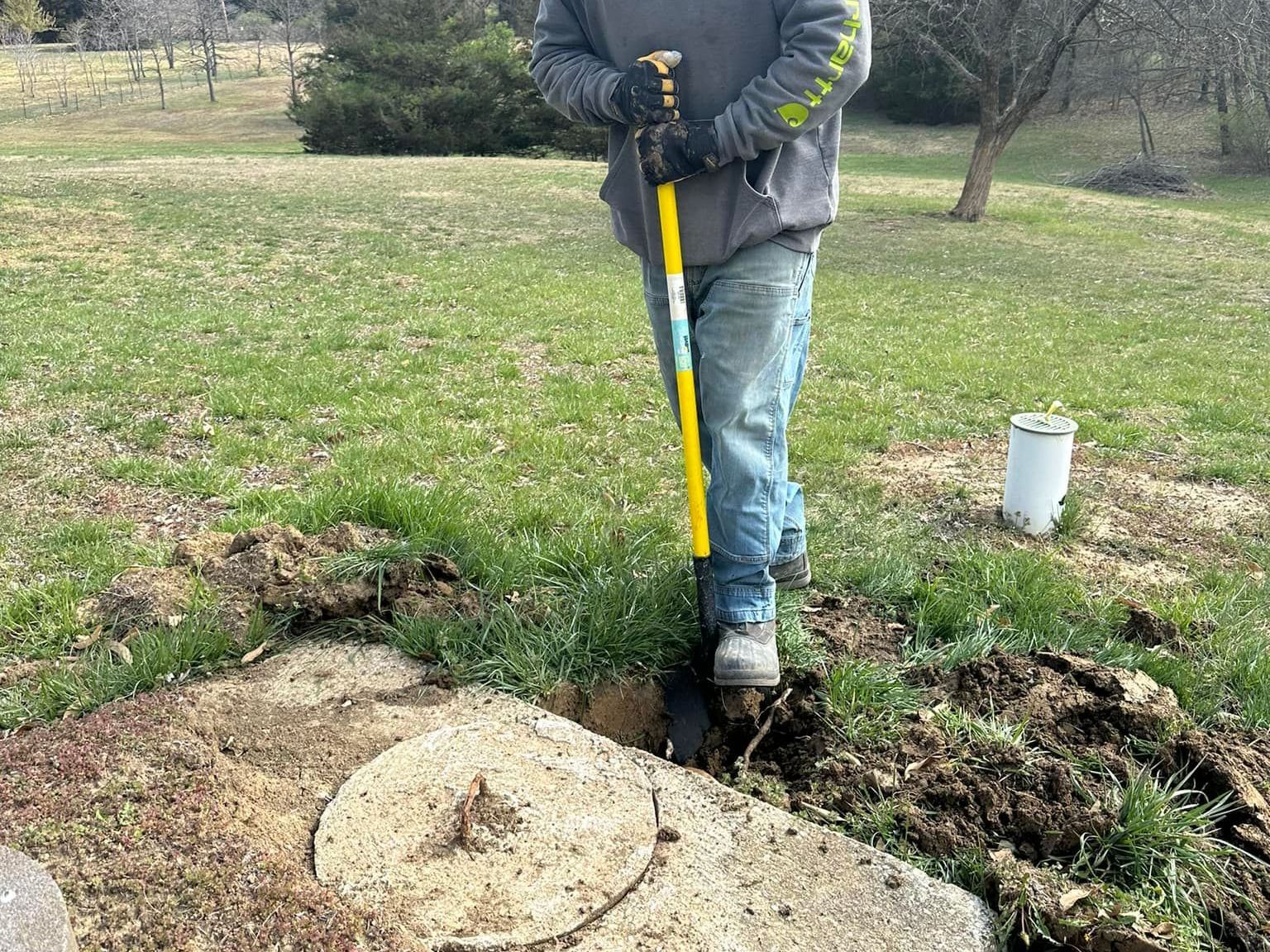 A man is digging a hole in the ground with a shovel.