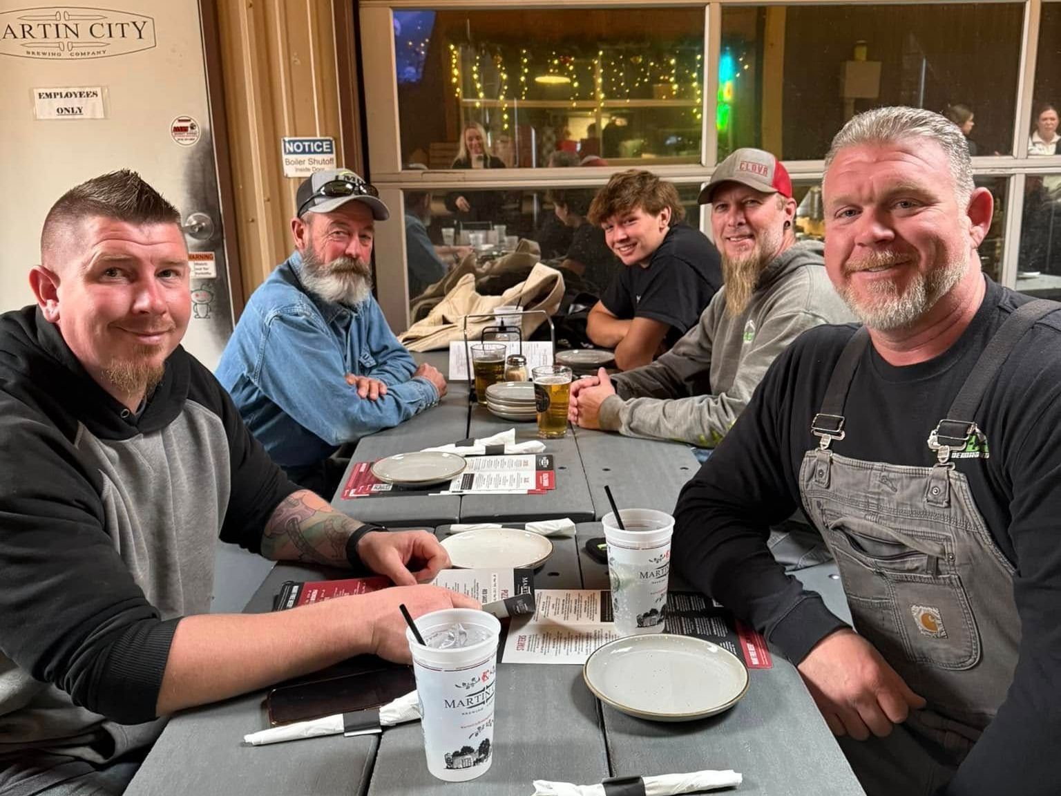 A group of men are sitting at a table with plates and cups.