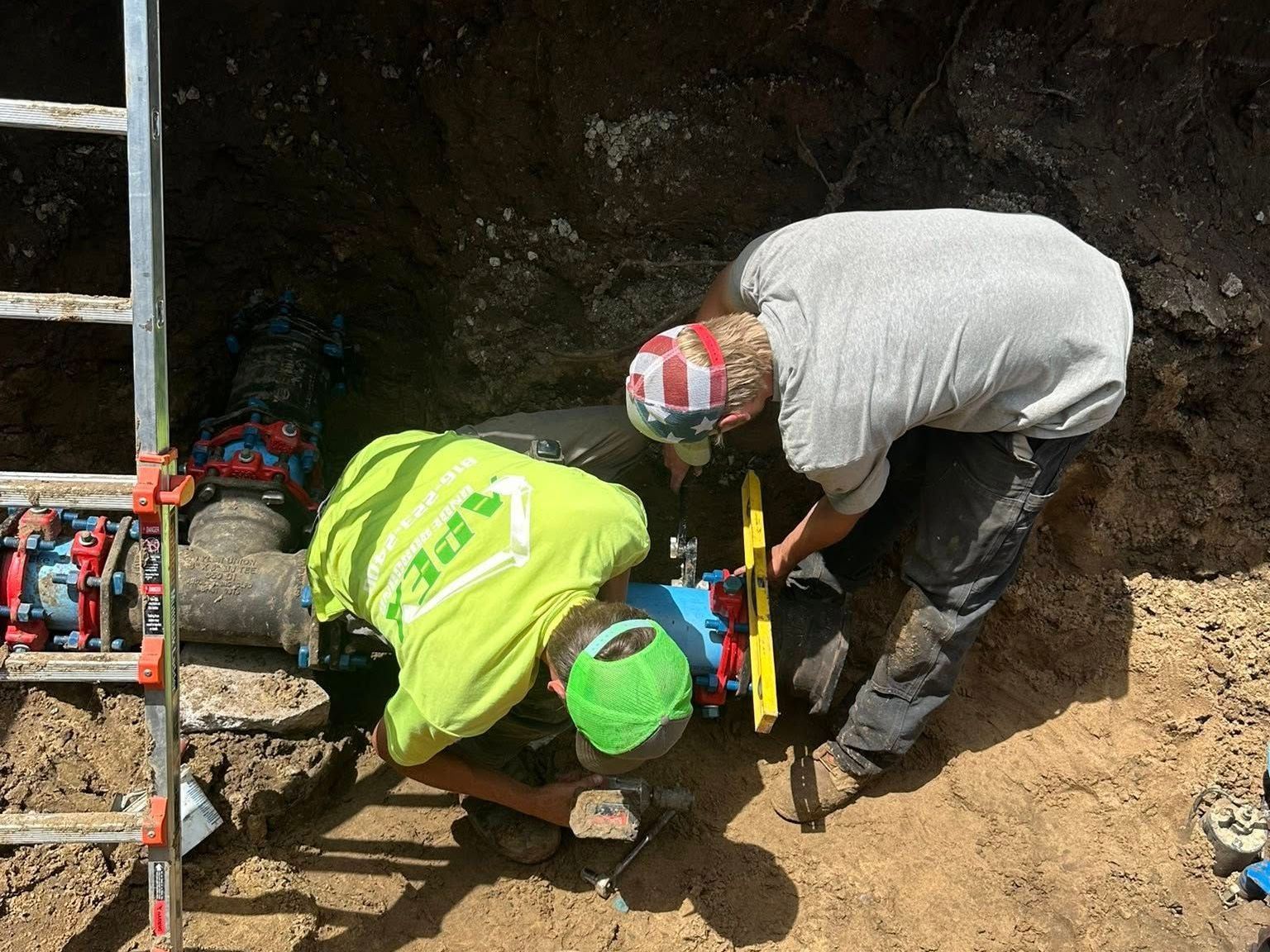 A man is digging a hole in the ground in front of a house.