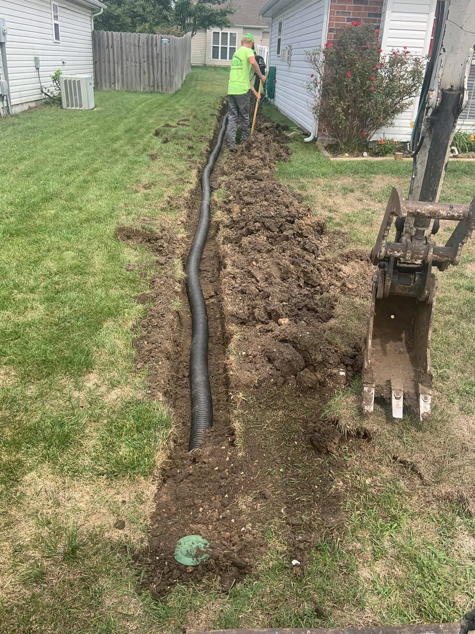 A man is digging a hole in the ground in front of a house.