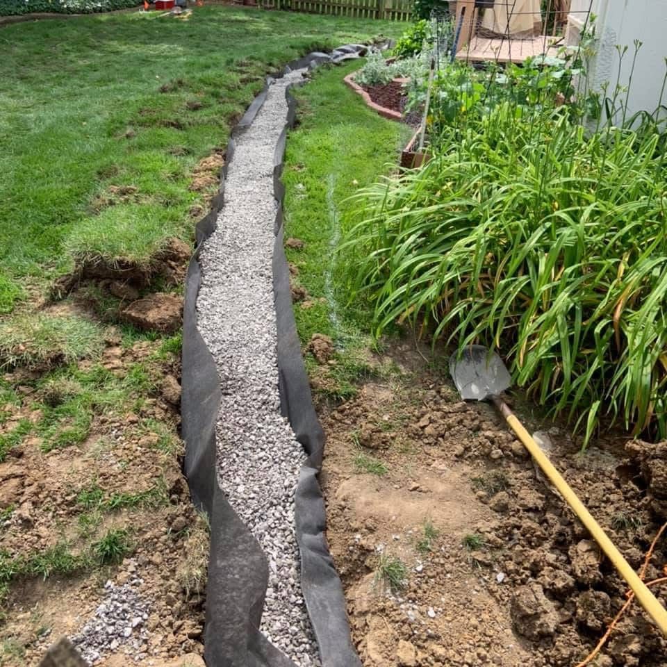 A shovel is sitting in the dirt next to a gravel path.