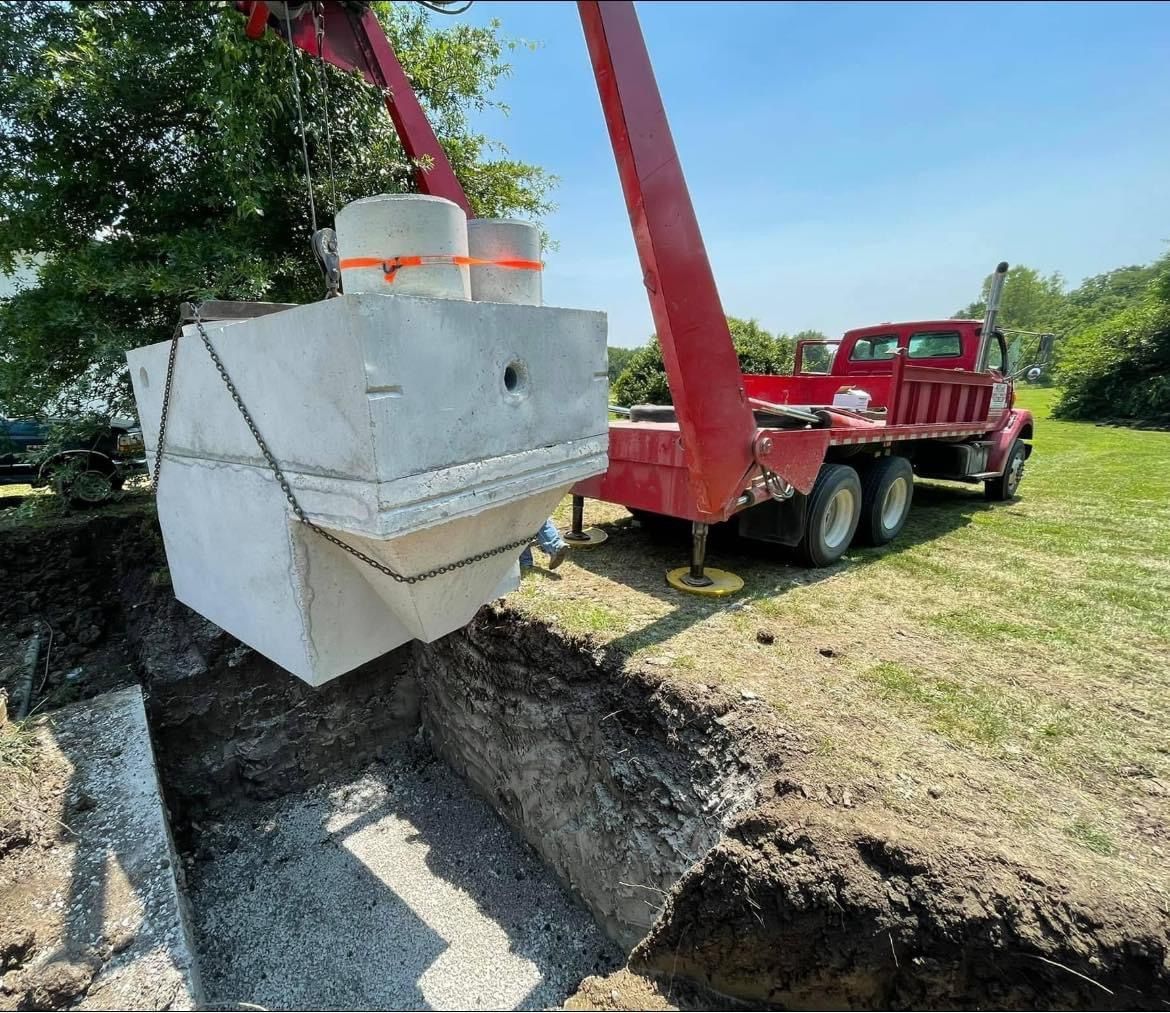 A red truck is carrying a large concrete block in a hole.