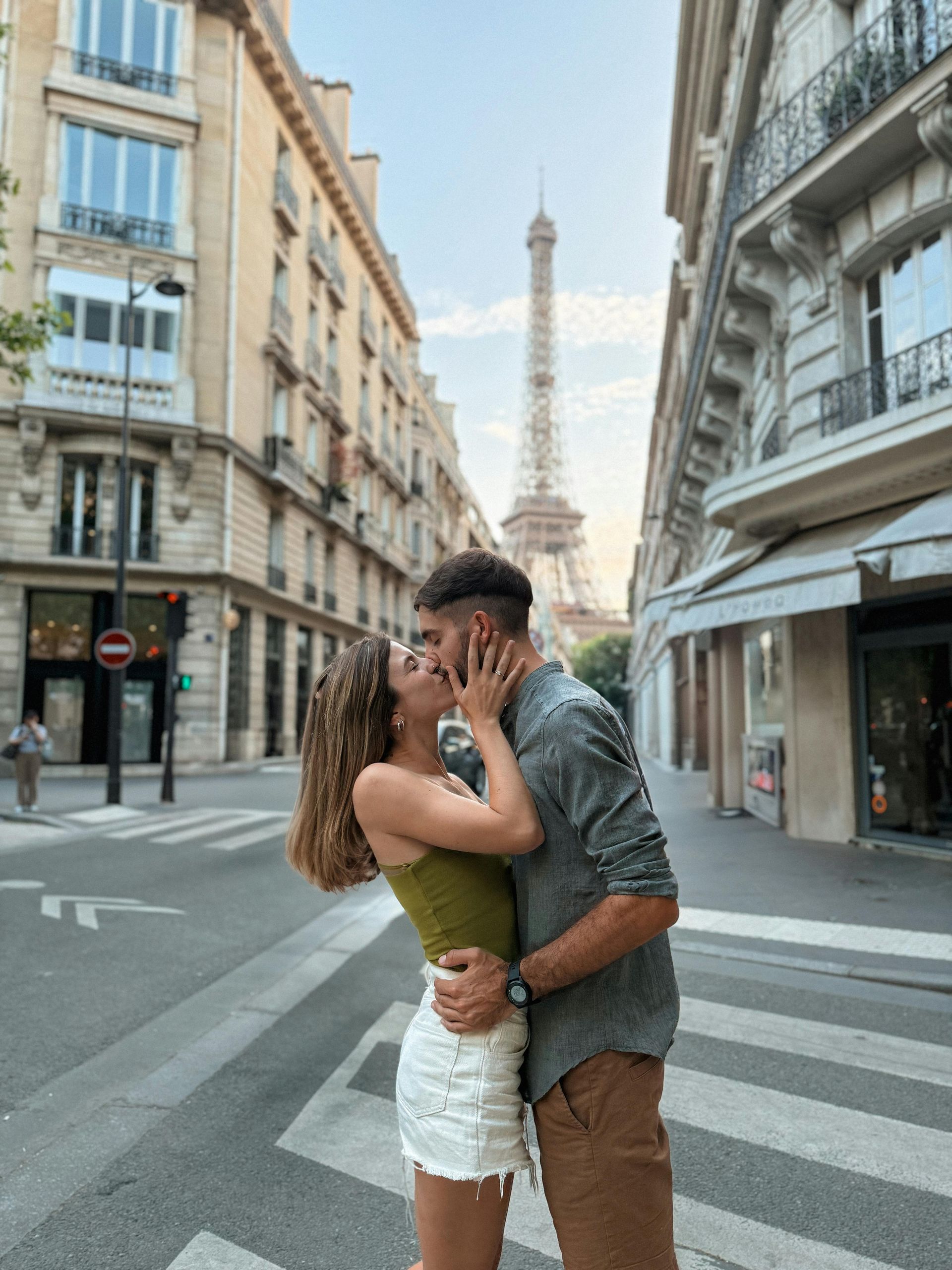Couple kissing on a Paris street, Eiffel Tower in the background.