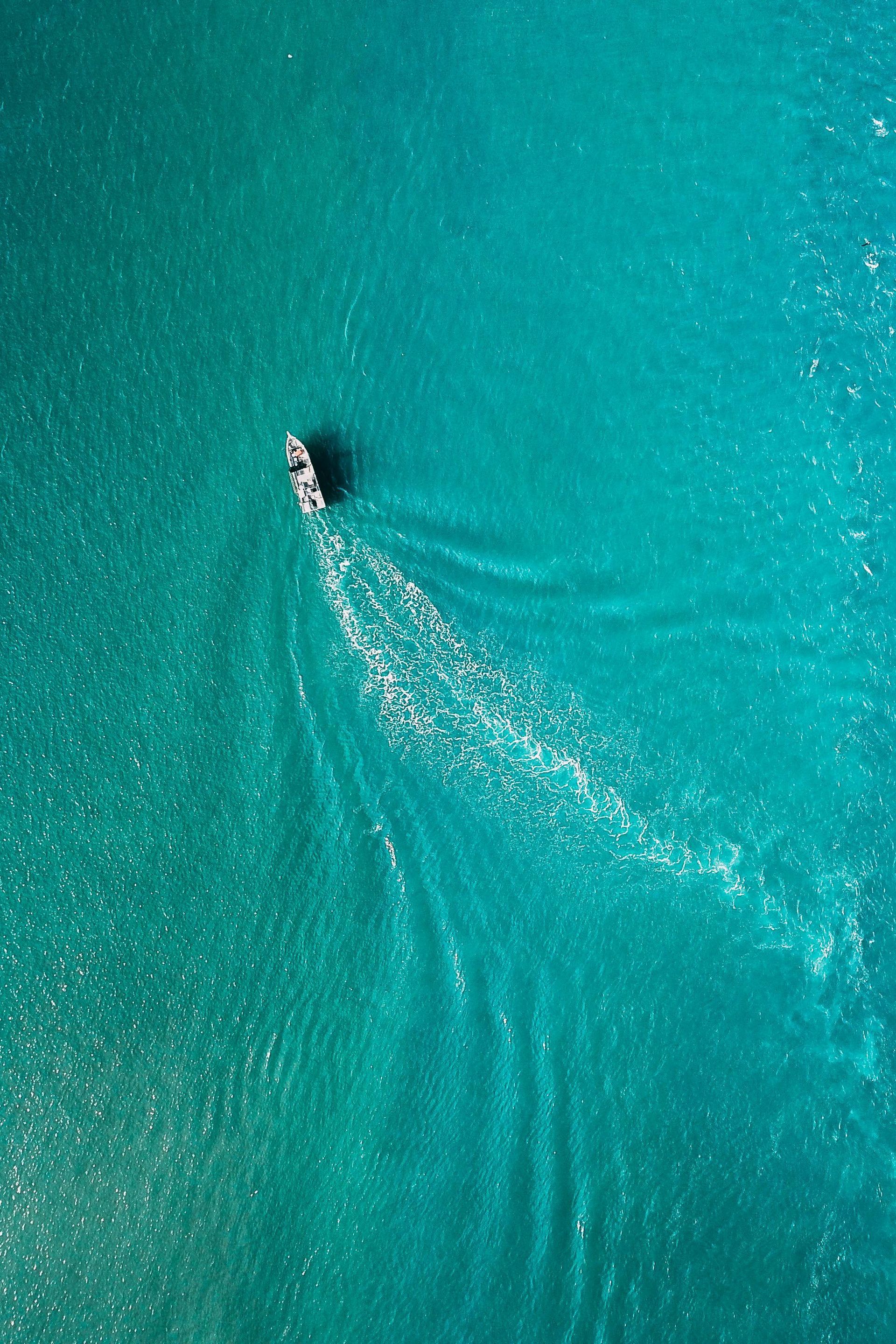 Boat sailing on turquoise water, leaving a white wake.