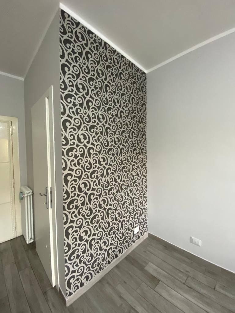Una stanza vuota con una carta da parati a fantasia sul muro.