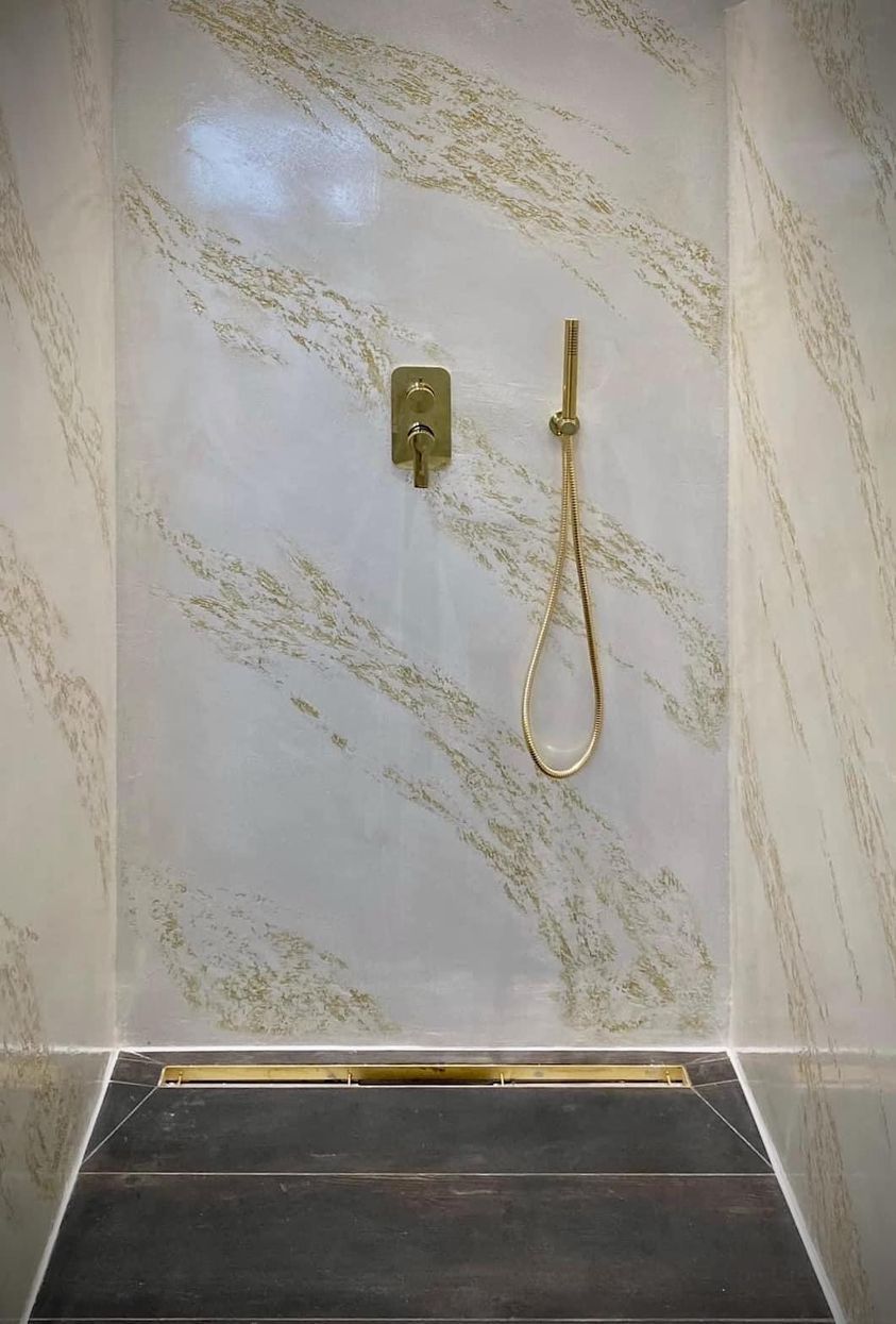 Un bagno con cabina doccia con parete in marmo e pavimento nero.