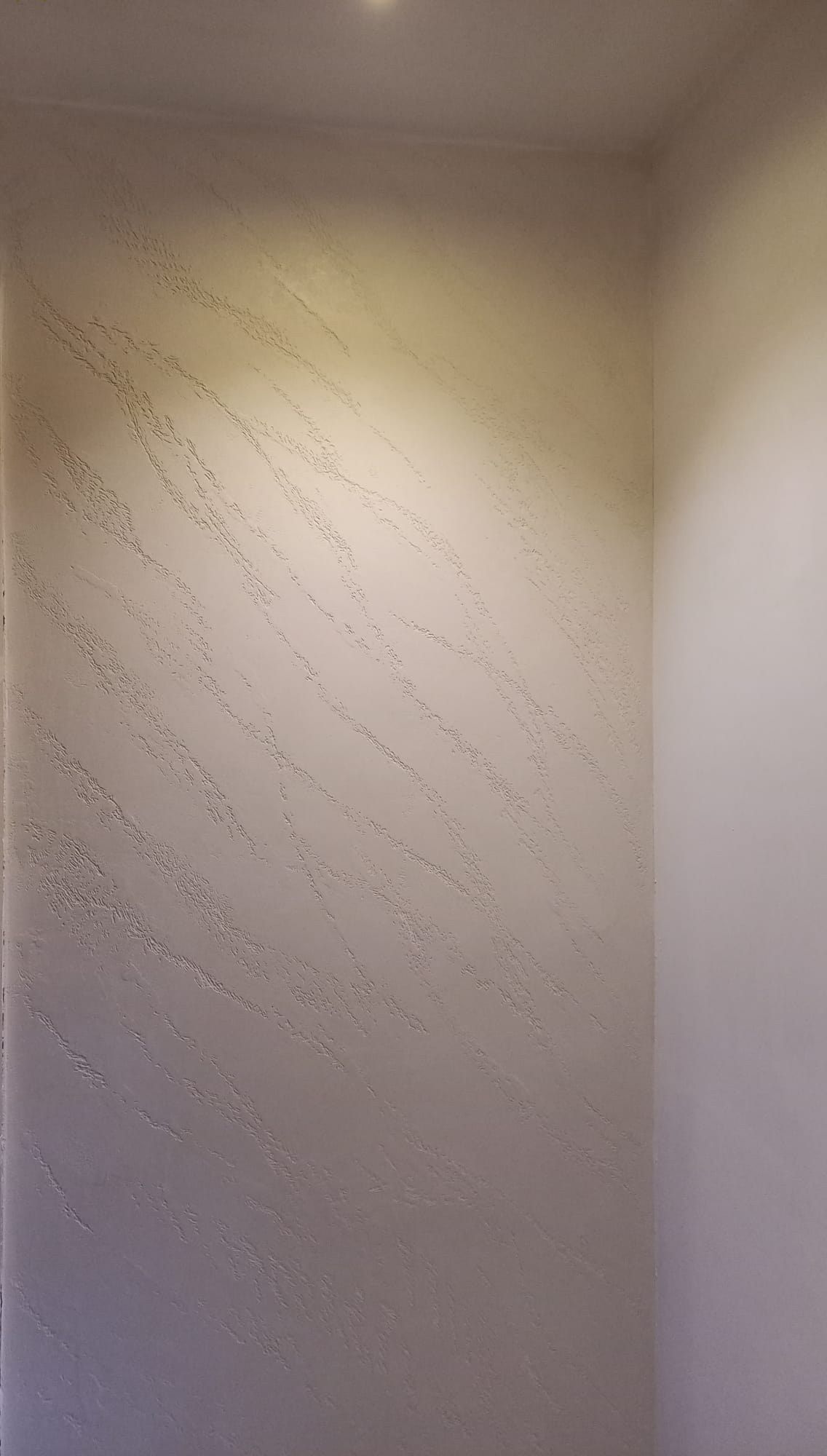 Una parete bianca con una luce in una stanza.