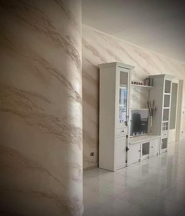 Un soggiorno con un centro di intrattenimento bianco e una parete di marmo.