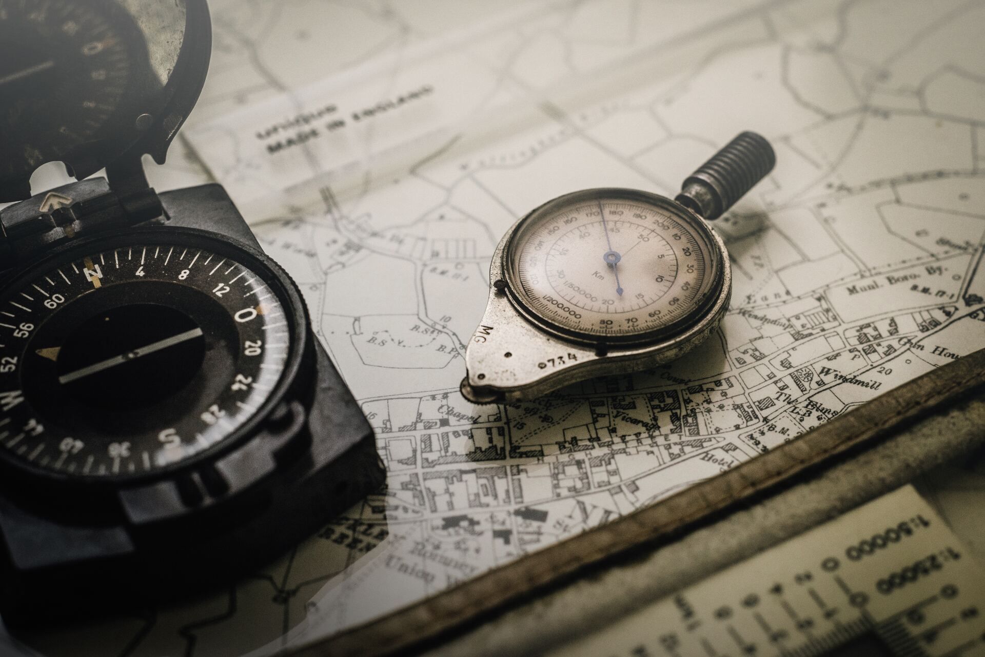 A compass and magnifying glass are sitting on top of a map.