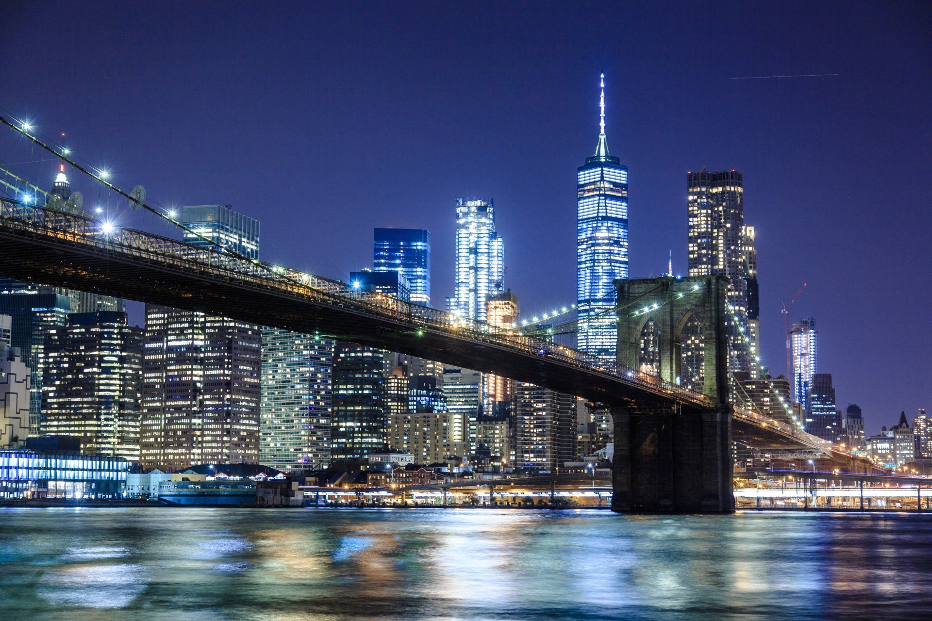 A bridge over a body of water with a city skyline in the background at night.