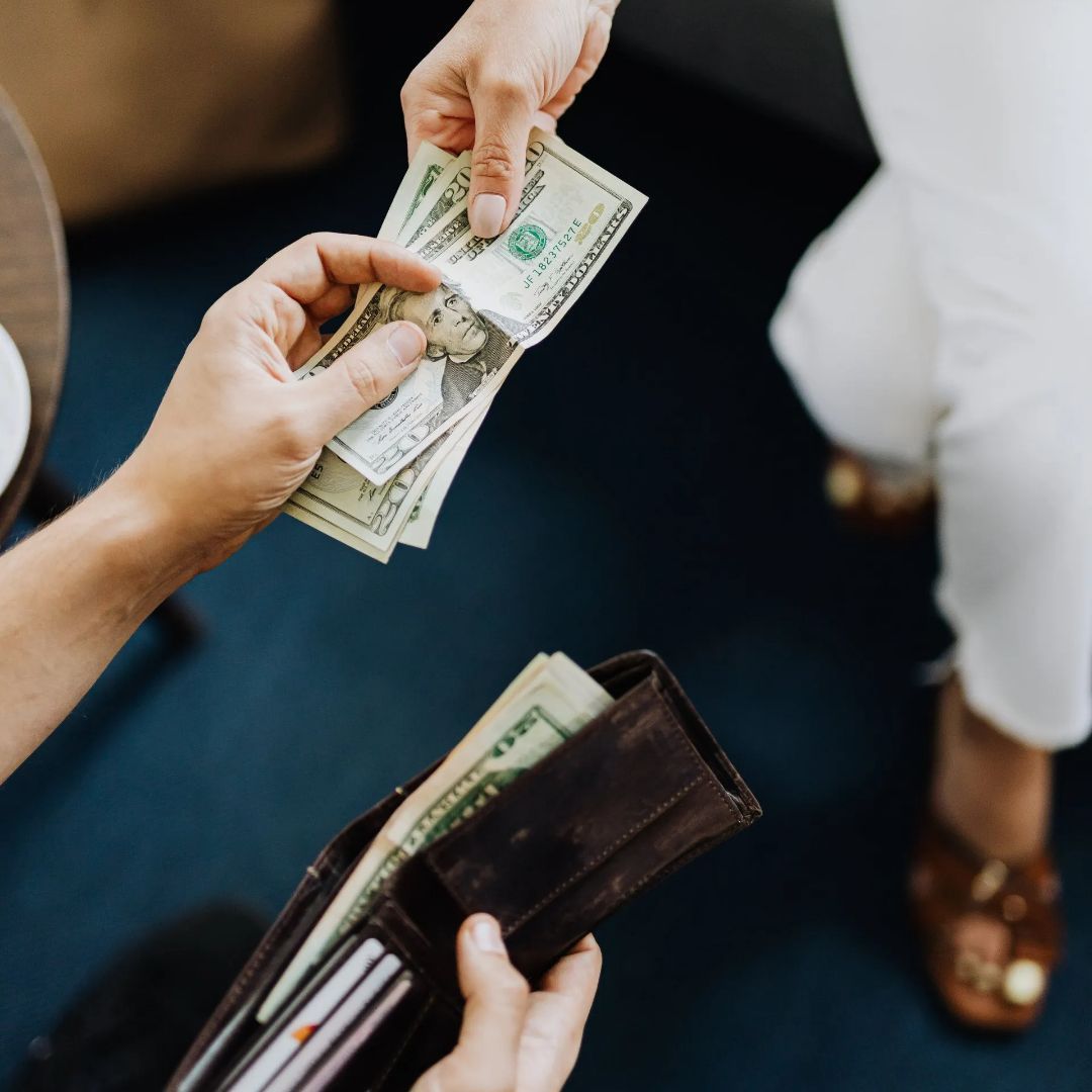 A person is handing a dollar bill to another person.