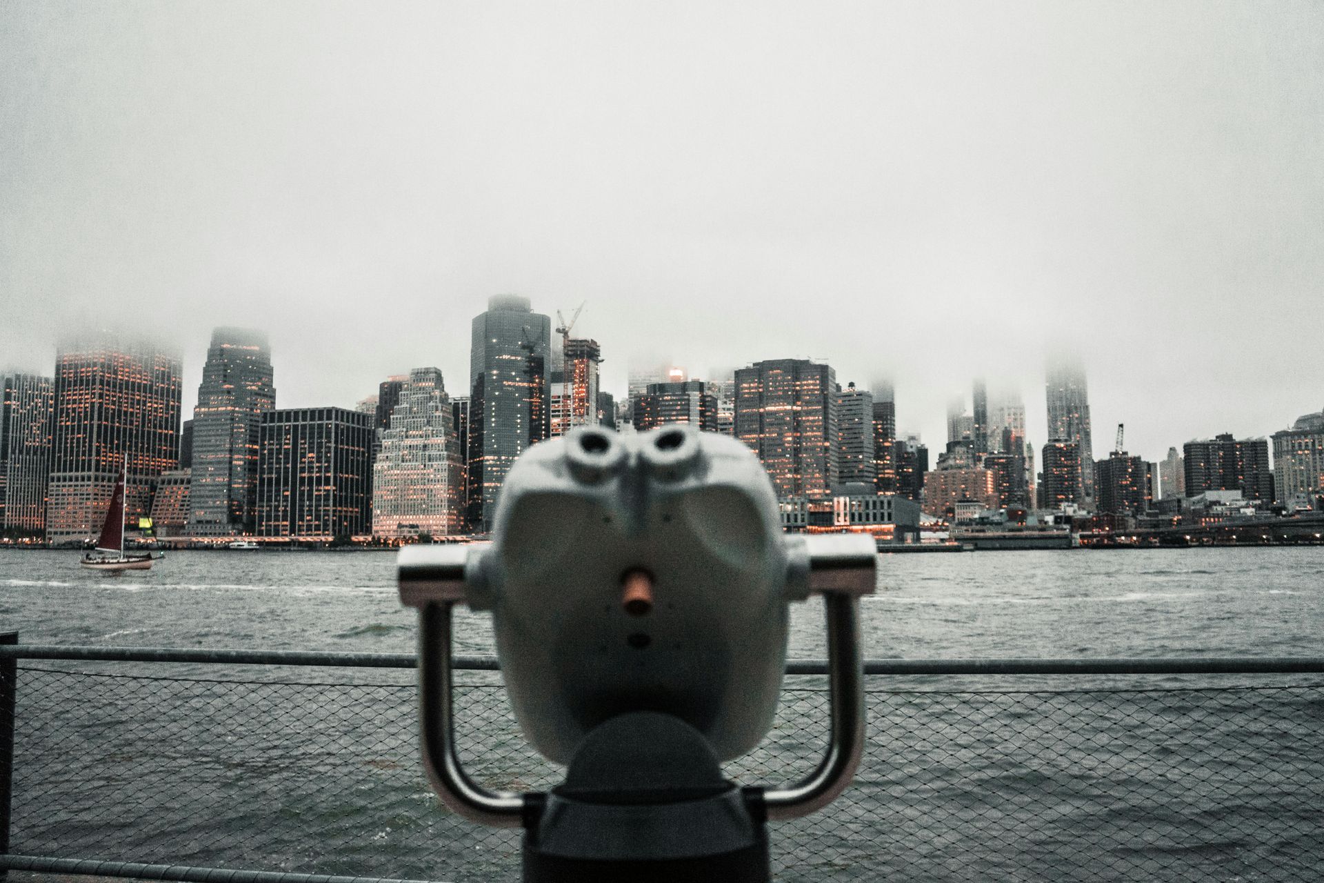 A pair of binoculars looking out over a body of water at a city skyline.