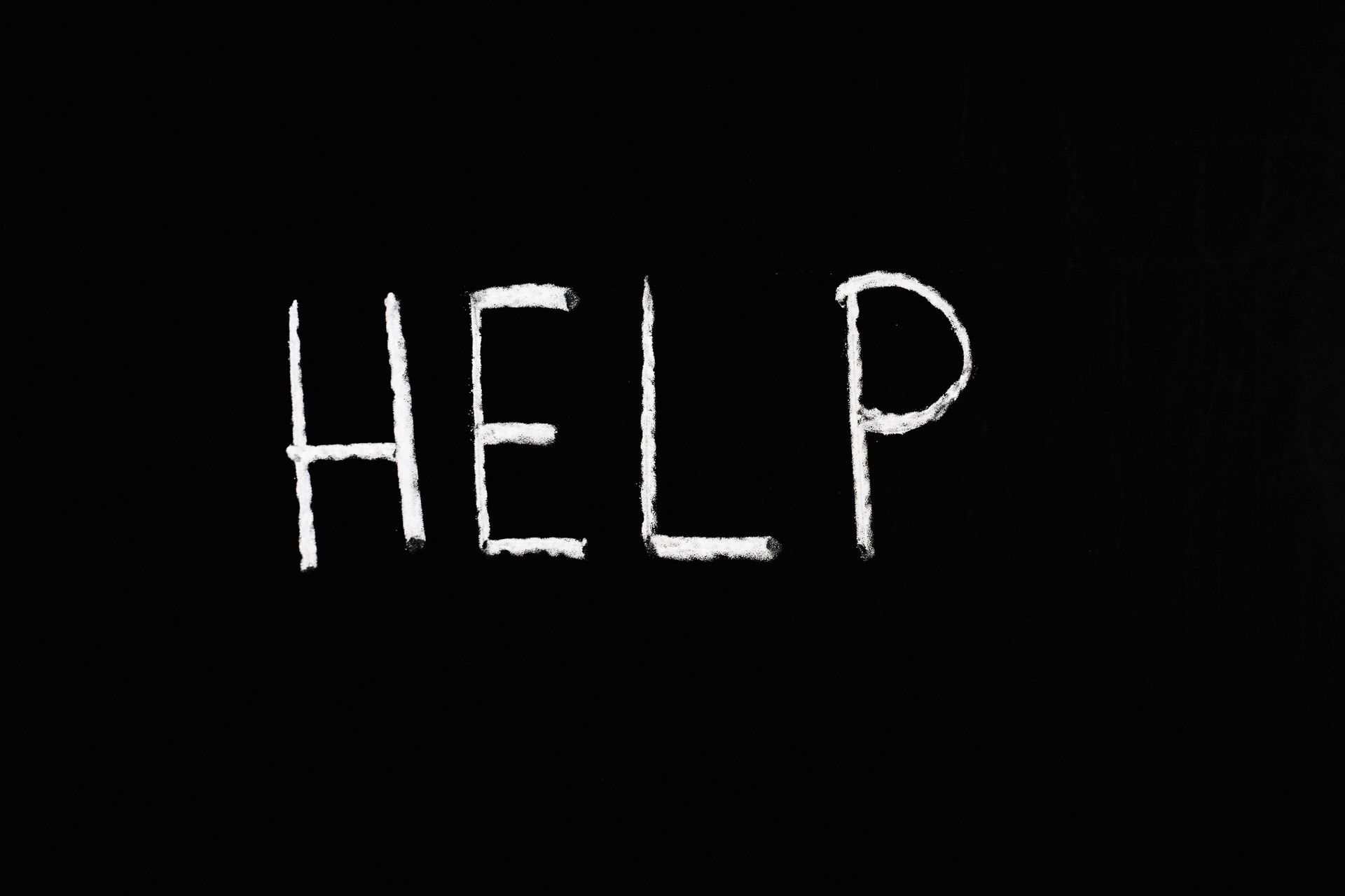 The word help is written in white chalk on a black background.