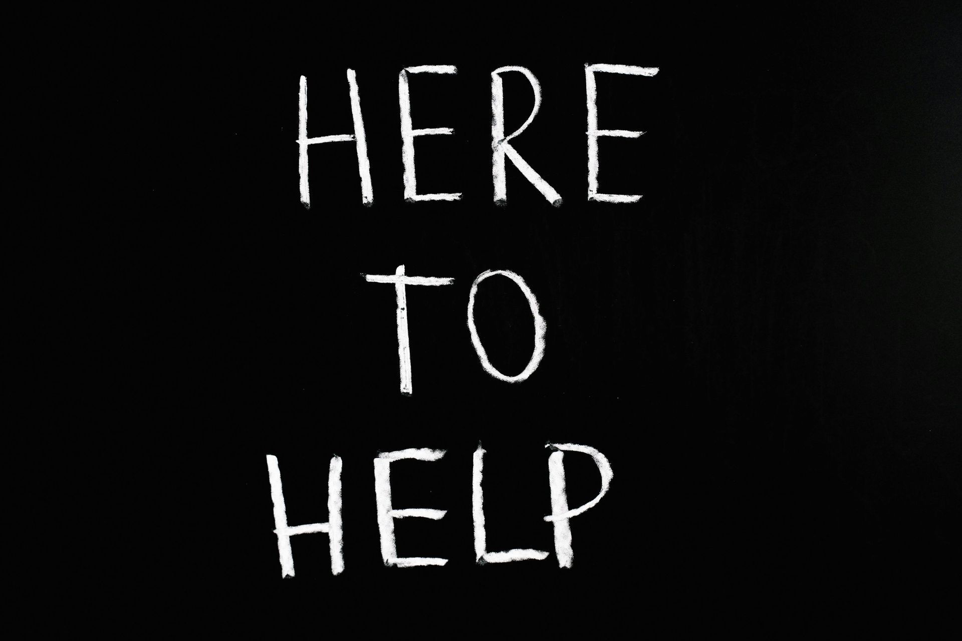 A blackboard with the words here to help written on it.