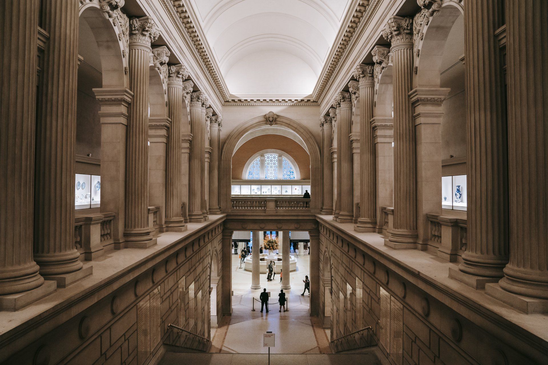 A large building with columns and people walking through it.
