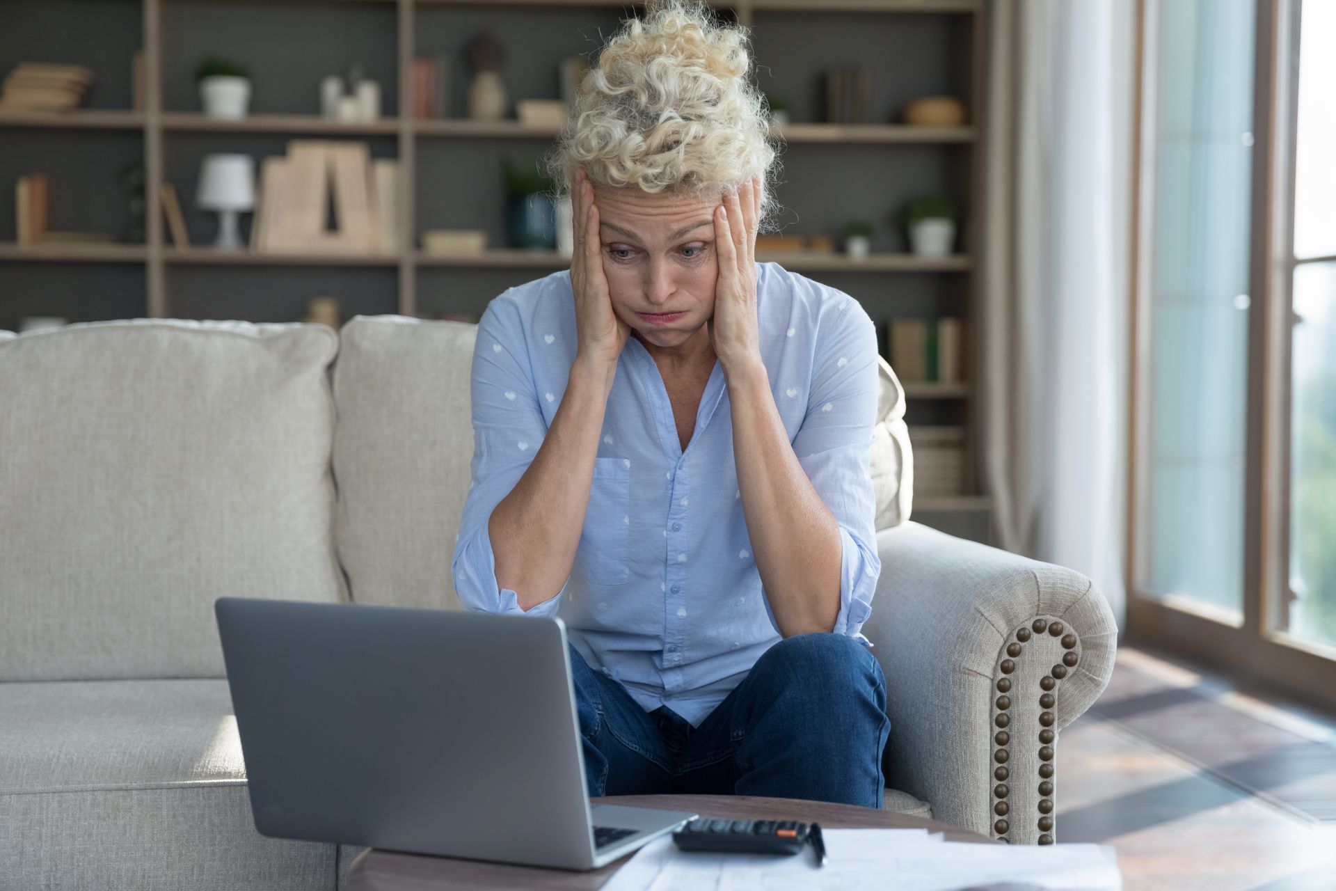 A woman is sitting on a couch using a laptop computer.