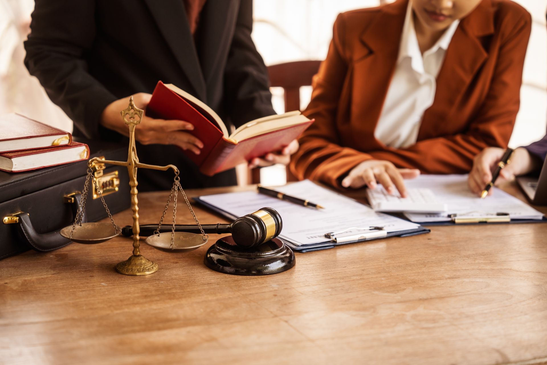 A group of lawyers are sitting at a table with a gavel and scales of justice.