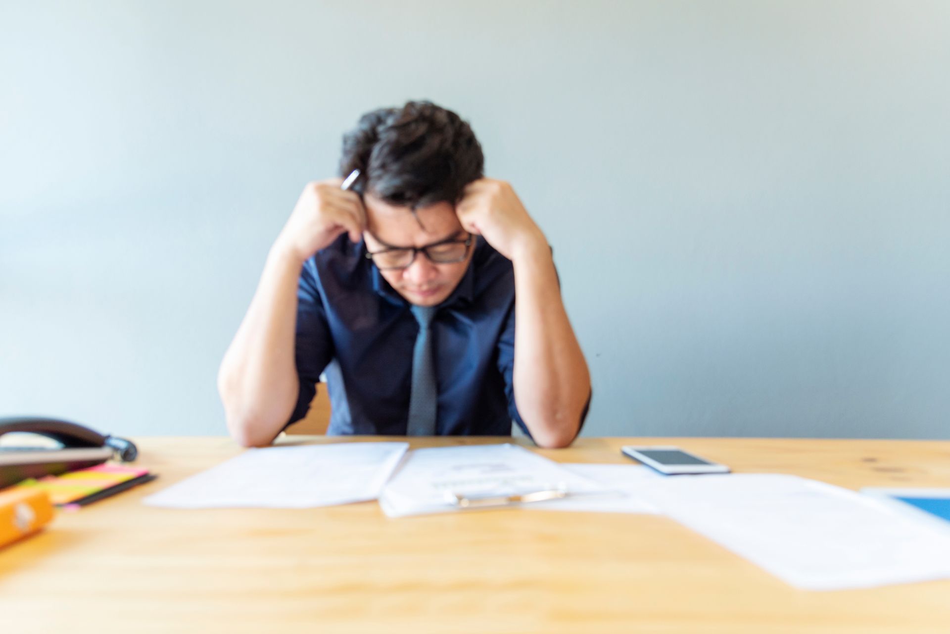 A man is sitting at a desk with his head in his hands.