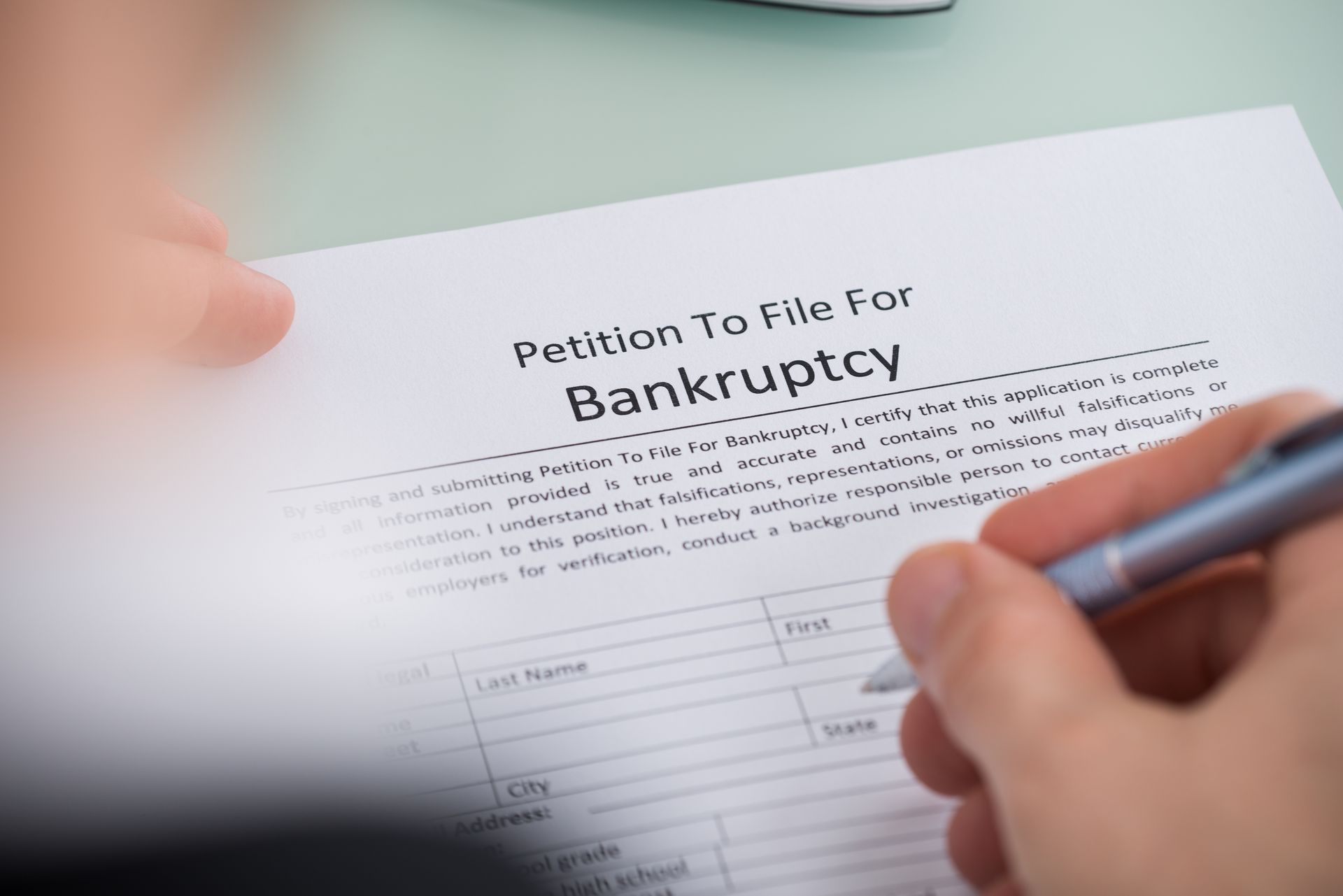 A person is signing a petition to file for bankruptcy.