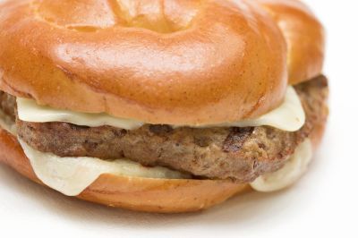 A close up of a hamburger with cheese on a bun on a white bun