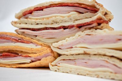 Three sandwiches are stacked on top of each other on a white surface.