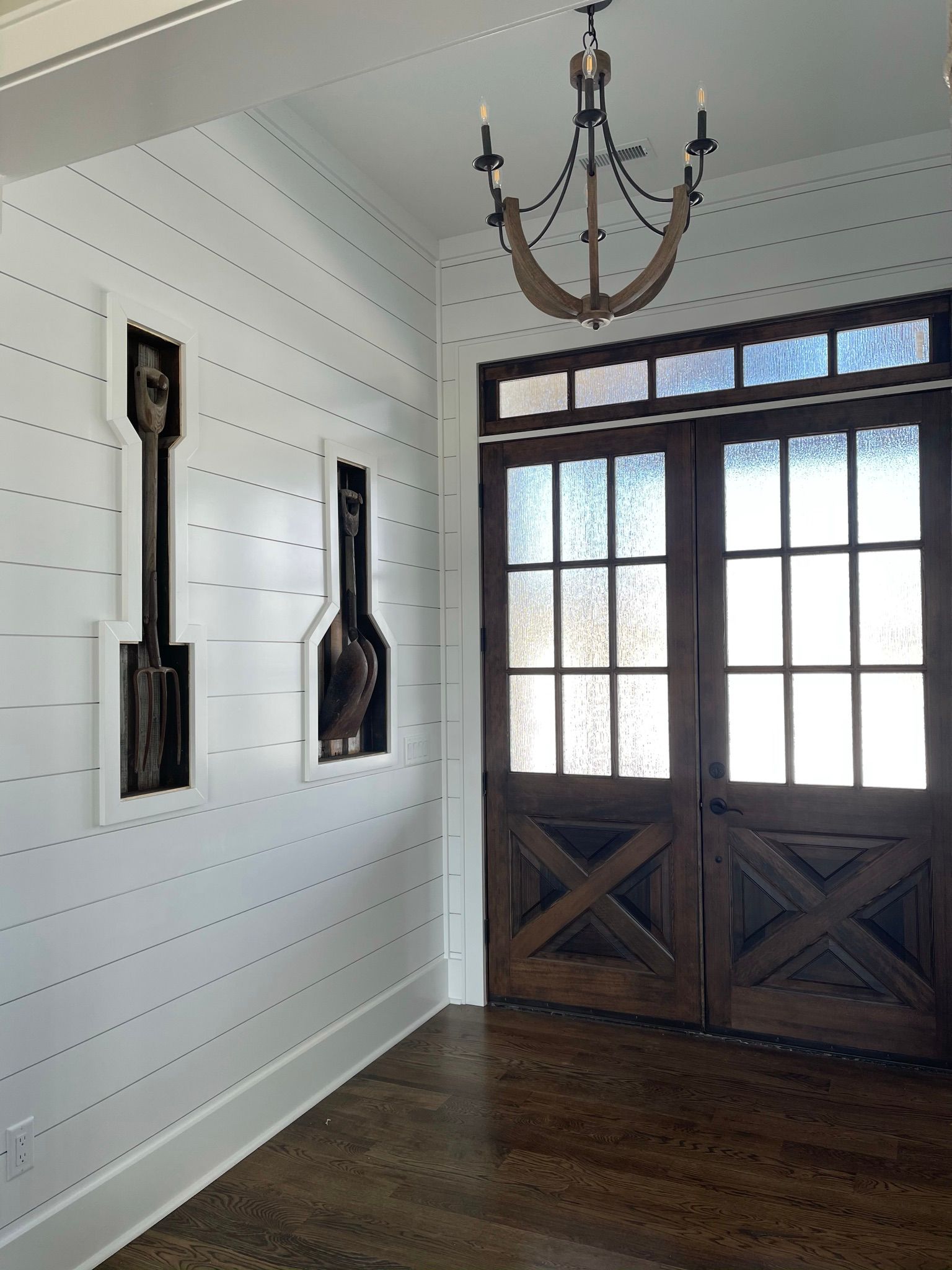 A hallway with wooden doors and a chandelier hanging from the ceiling.