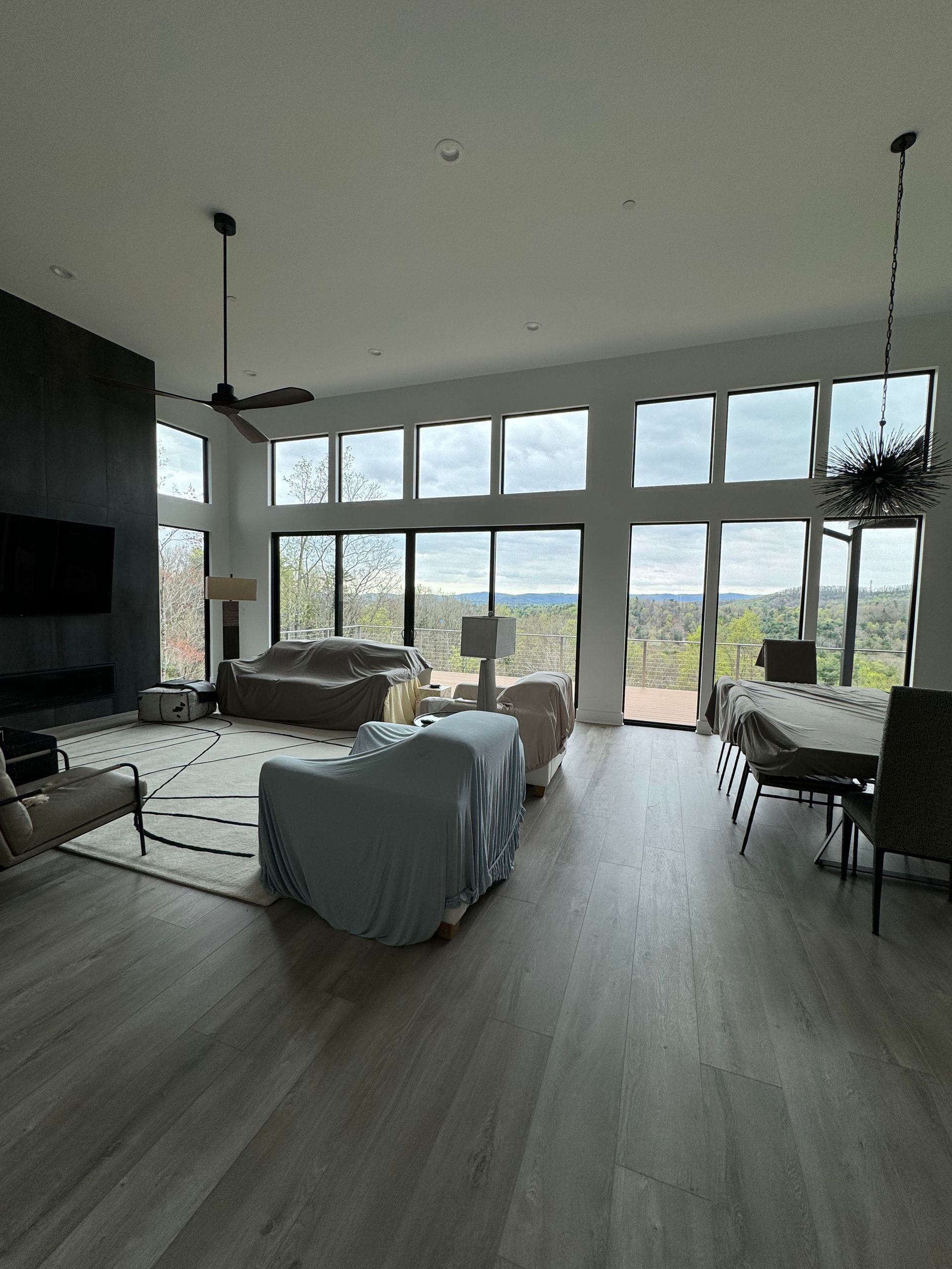 A living room with a lot of windows and a ceiling fan.