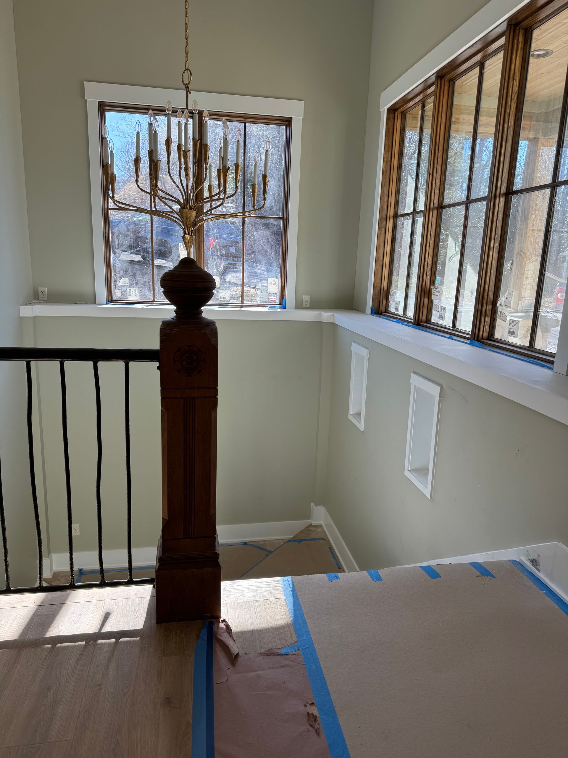 A staircase with a wooden railing and a chandelier hanging from the ceiling.