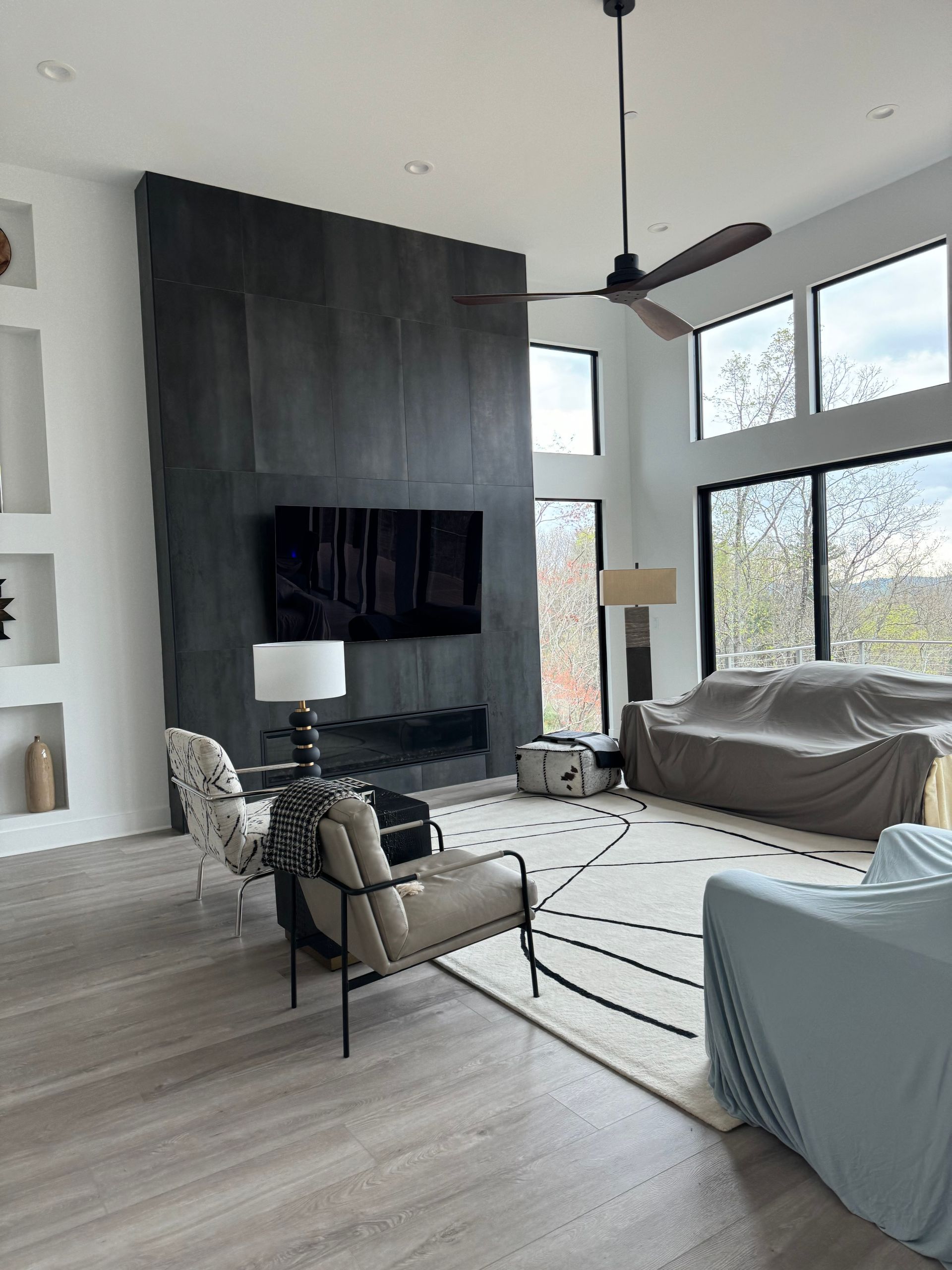 A living room with a fireplace , couch , chairs and a ceiling fan.