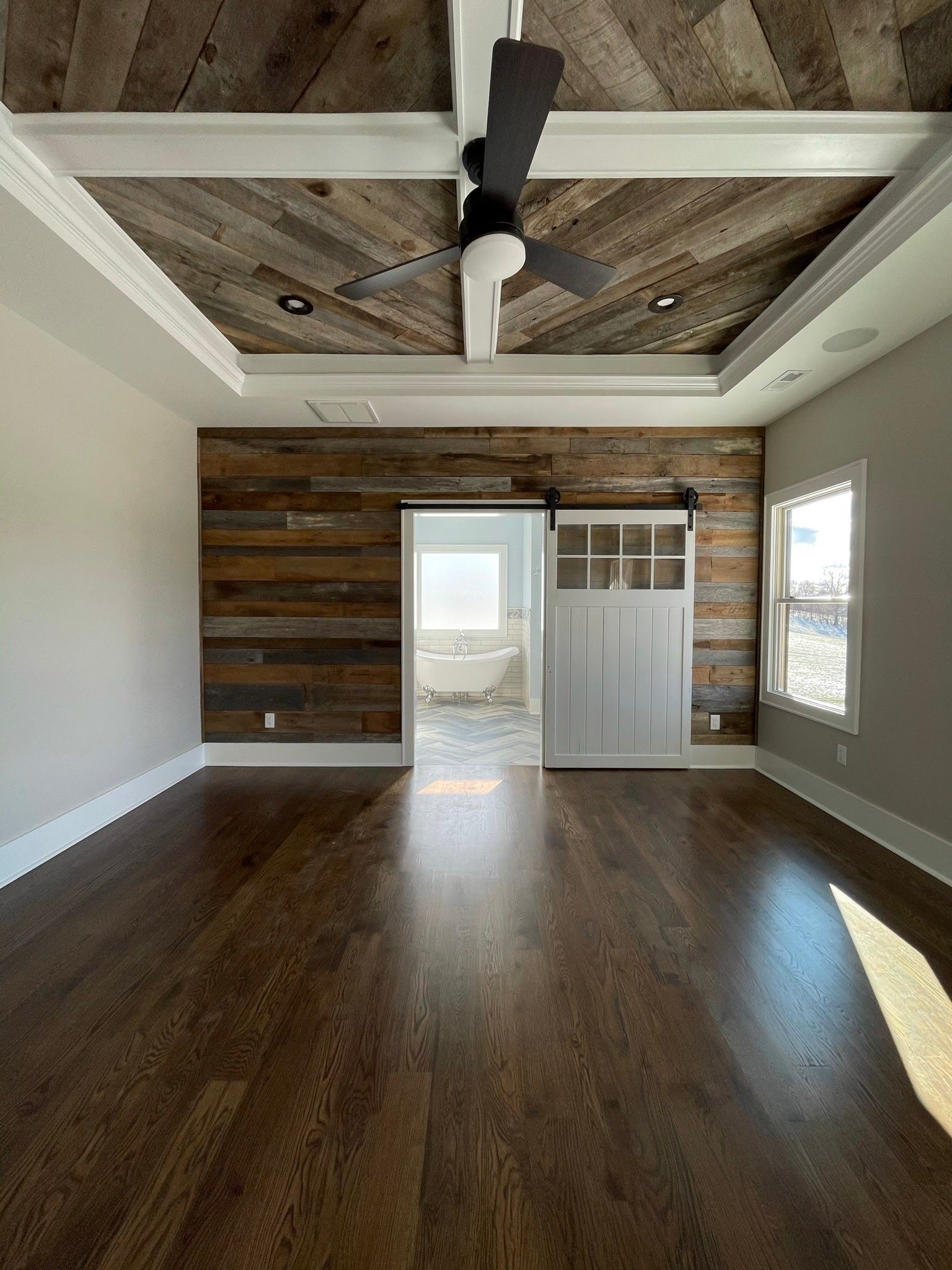 An empty room with a wooden wall and ceiling fan.